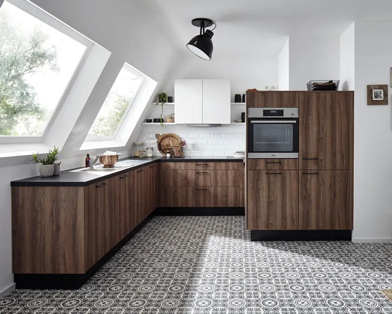 Eckküche mit Holzfronten, schwarzer Arbeitsplatte, Backofen und gemustertem Fliesenboden